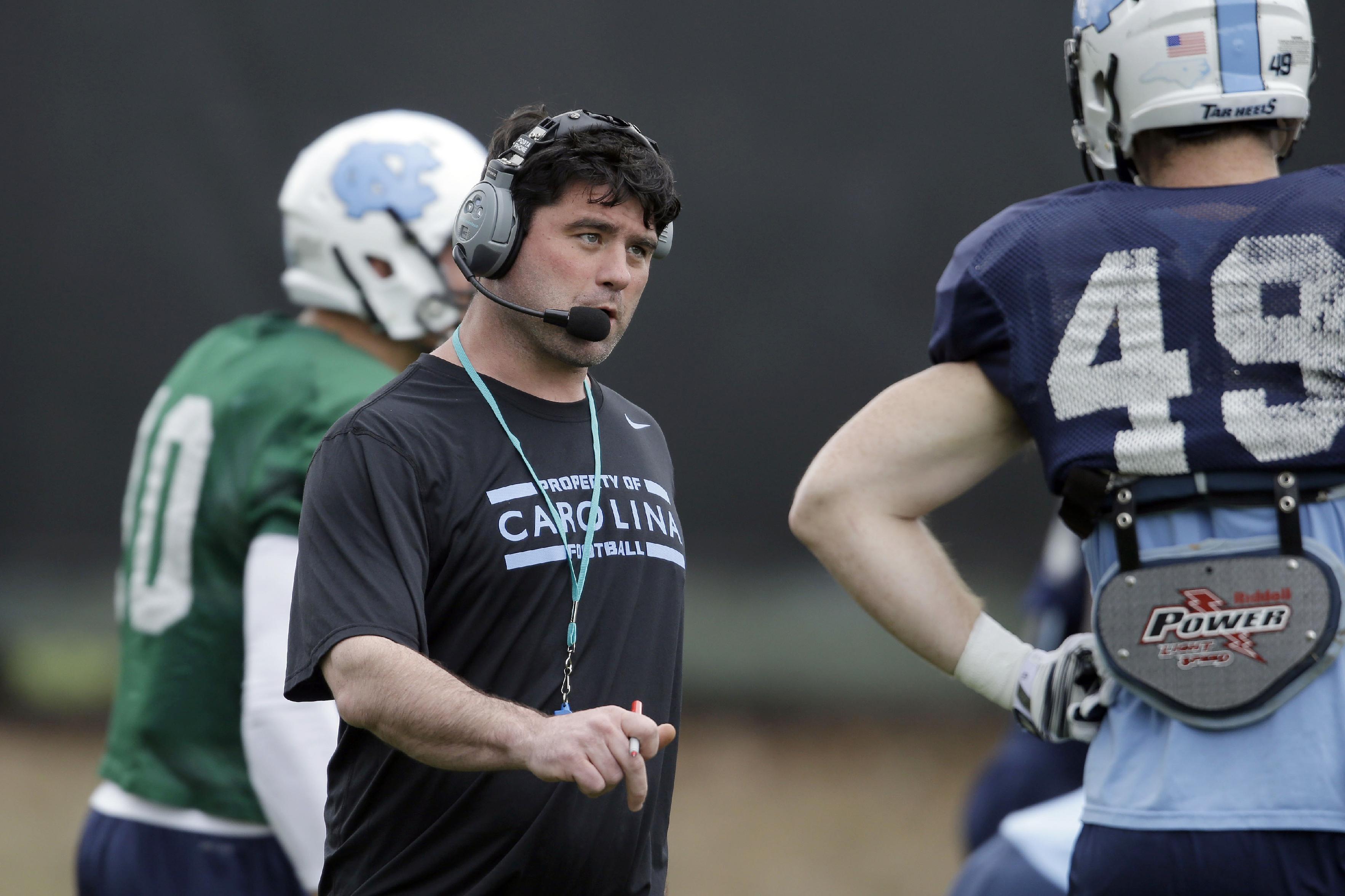 In this photo taken Wednesday, April 9, 2014 North Carolina's new assistant head coach for offense and tight ends Seth Littrell speaks with tight end Eric Albright (49) during an NCAA college football spring practice in Chapel Hill, N.C. After spending the last two seasons at Indiana, Littrell is preparing for his first season with the Tar Heels. (AP Photo/Gerry Broome)