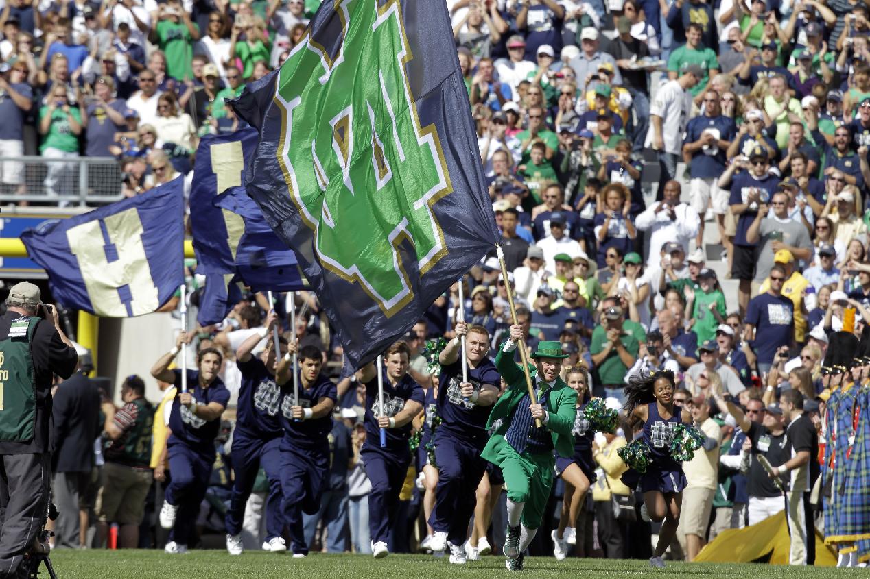 In this Sept. 8, 2012 photo, a Notre Dame mascot and cheerleaders helps lead the team on to field before an NCAA college football game against Purdue in South Bend, Ind. Ahead of the 2014 college football season, the AP asked its panel of Top 25 voters, who are known for ranking the nation's top teams each week, to weigh in on which stadium had the best game day atmosphere. Notre Dame Stadium has its Touchdown Jesus, looming over one end zone and recognition from the panel. (AP Photo/Michael Conroy, File)