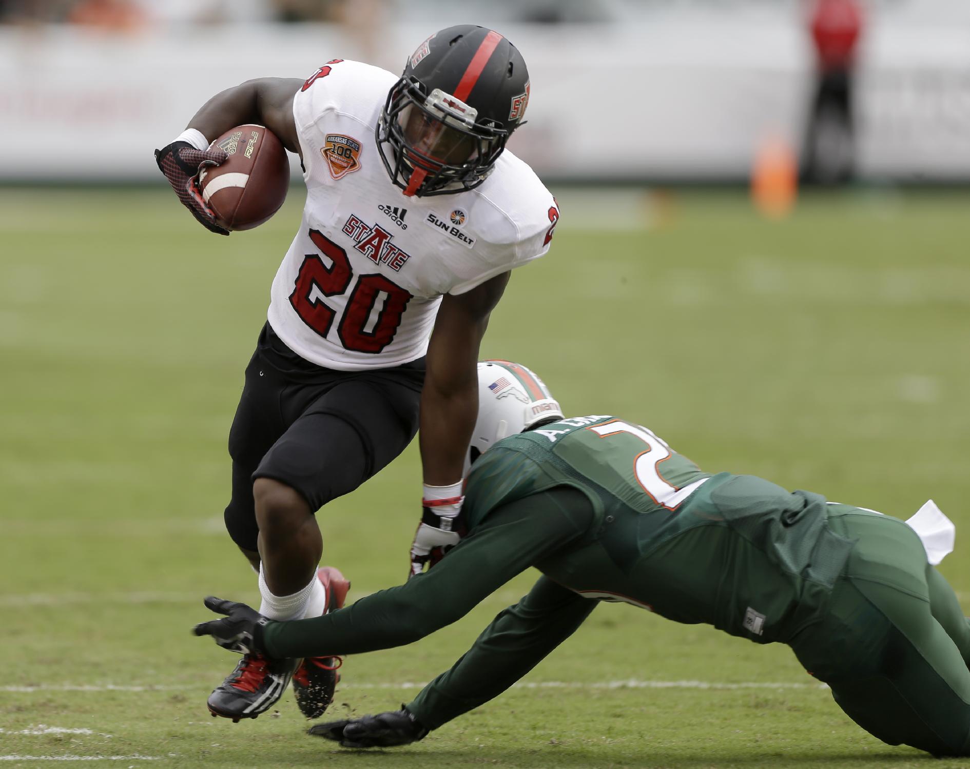 Arkansas State wide receiver Brandon Cox (20) is tackled by Miami defensive back Antonio Crawford (21) during the first half of an NCAA college  football game in Miami Gardens, Fla., Saturday, Sept. 13, 2014. (AP Photo/Alan Diaz)