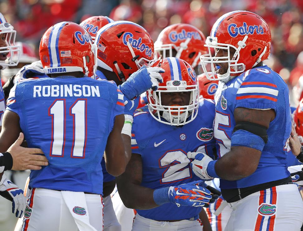 Florida running back Kelvin Taylor, center, celebrates a touchdown run with teammates including Demarcus Robinson (11) and Chaz Green, right, during the first half of an NCAA college football game against Georgia in Jacksonville, Fla., Saturday, Nov. 1, 2014. (AP Photo/Stephen B. Morton)