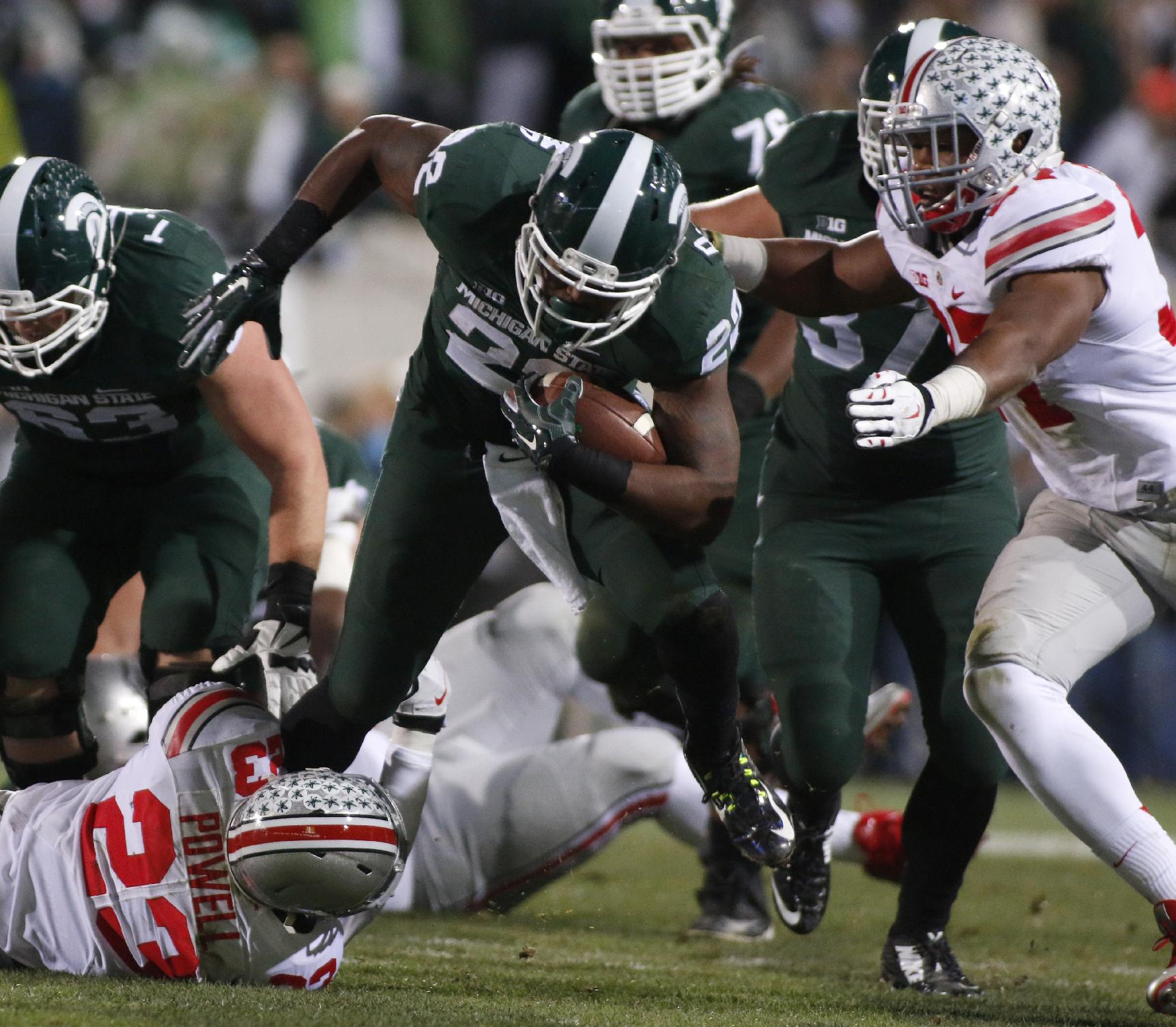 Ohio State's Tyvis Powell (23) and Joshua Perry, right, stop Michigan State's Delton Williams, center, during the second quarter of an NCAA college football game, Saturday, Nov. 8, 2014, in East Lansing, Mich. (AP Photo/Al Goldis)