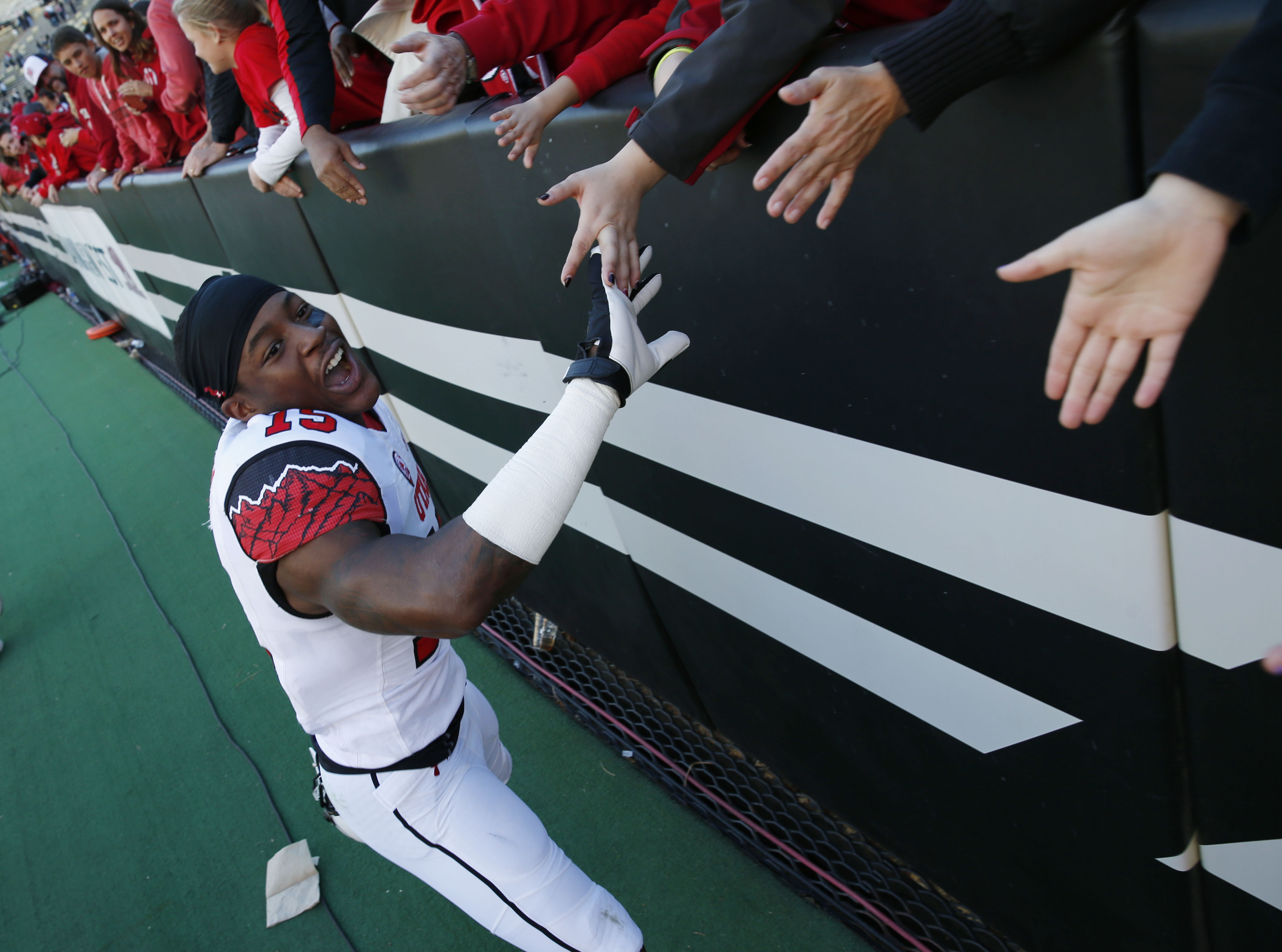 Utah defensive back Dominique Hatfield is congratulated by fans as he leaves the field Utah's 38-34 victory over Colorado in an NCAA college football game in Boulder, Colo., Saturday, Nov. 29, 2014. Hatfield intercepted a pass and scored the winning touchdown in the fourth quarter to secure the win for Utah. (AP Photo/David Zalubowski)