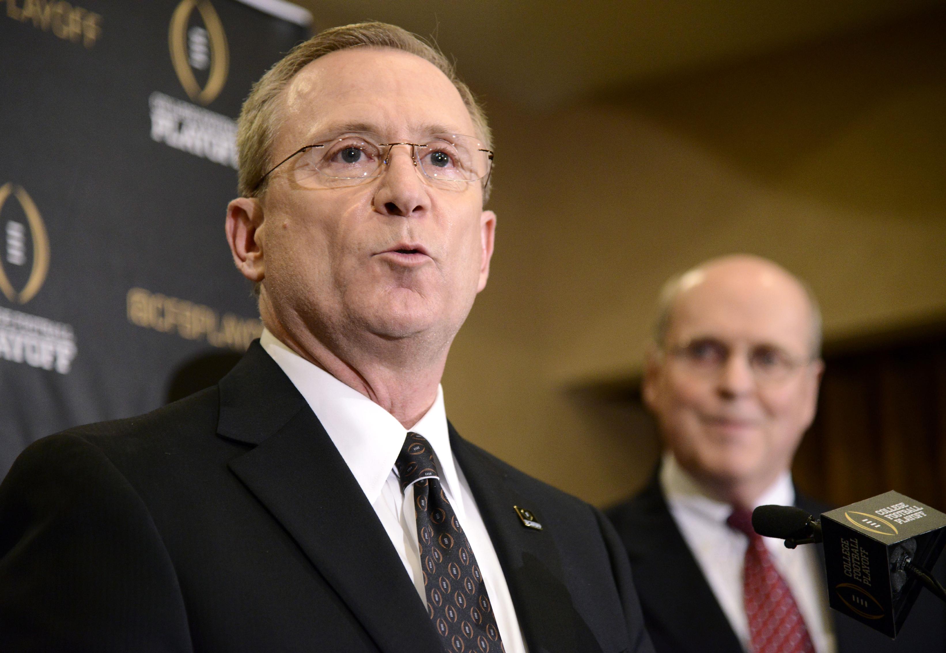 FILE - In this Oct. 28, 2014, file photo, Jeff Long, left, chair of the college football playoff selection committee, speaks to the media about the first NCAA College Football Playoff rankings as Bill Hancock, executive director of the committee, stands near during a news conferenc in Grapevine, Texas. The College Football Playoff selection committee will reveal its final top 25 rankings and set the four-team field for the College Football Playoff on Sunday. (AP Photo/Tim Sharp, File)