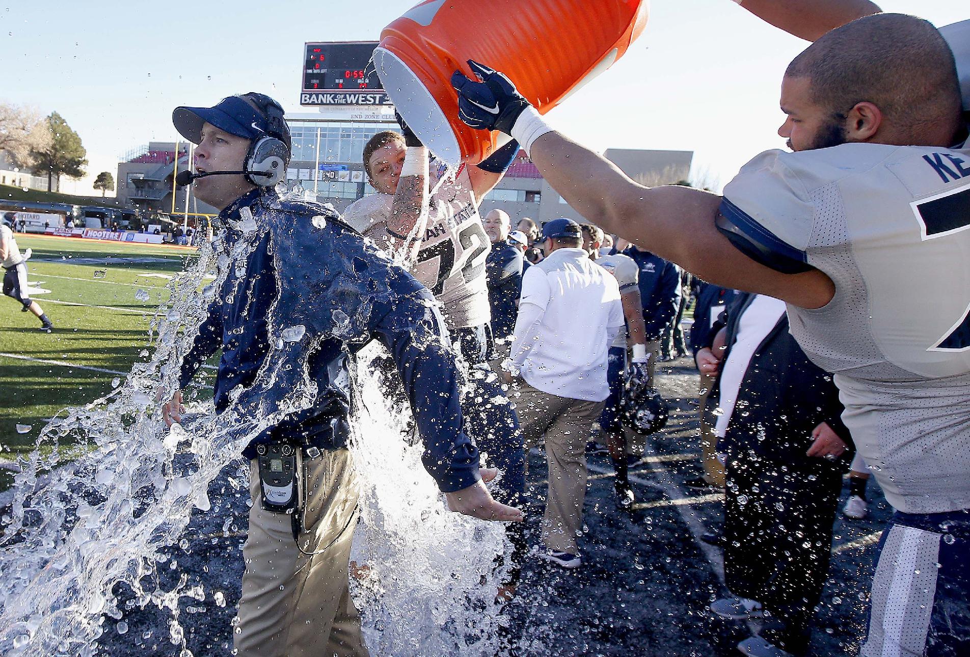 Utah State coach Matt Wells, left, gets hit with water by Tyshon Mosley (72) and Kevin Whimpey, right. (AP Photo/Ross D. Franklin)