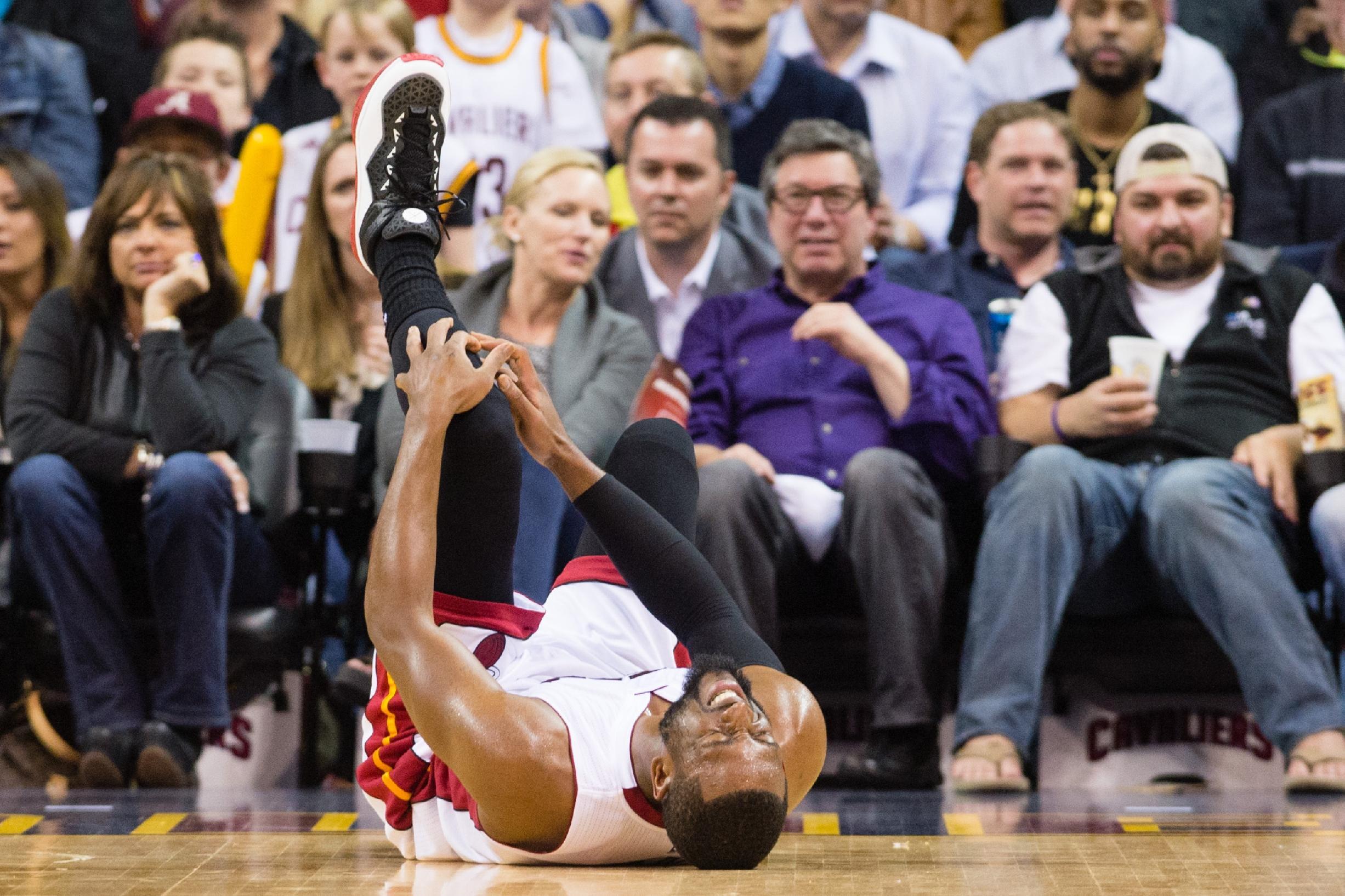 Dwayne Wade reacts after injuring his knee during the first half against the Cavaliers. (Jason Miller/Getty Images)