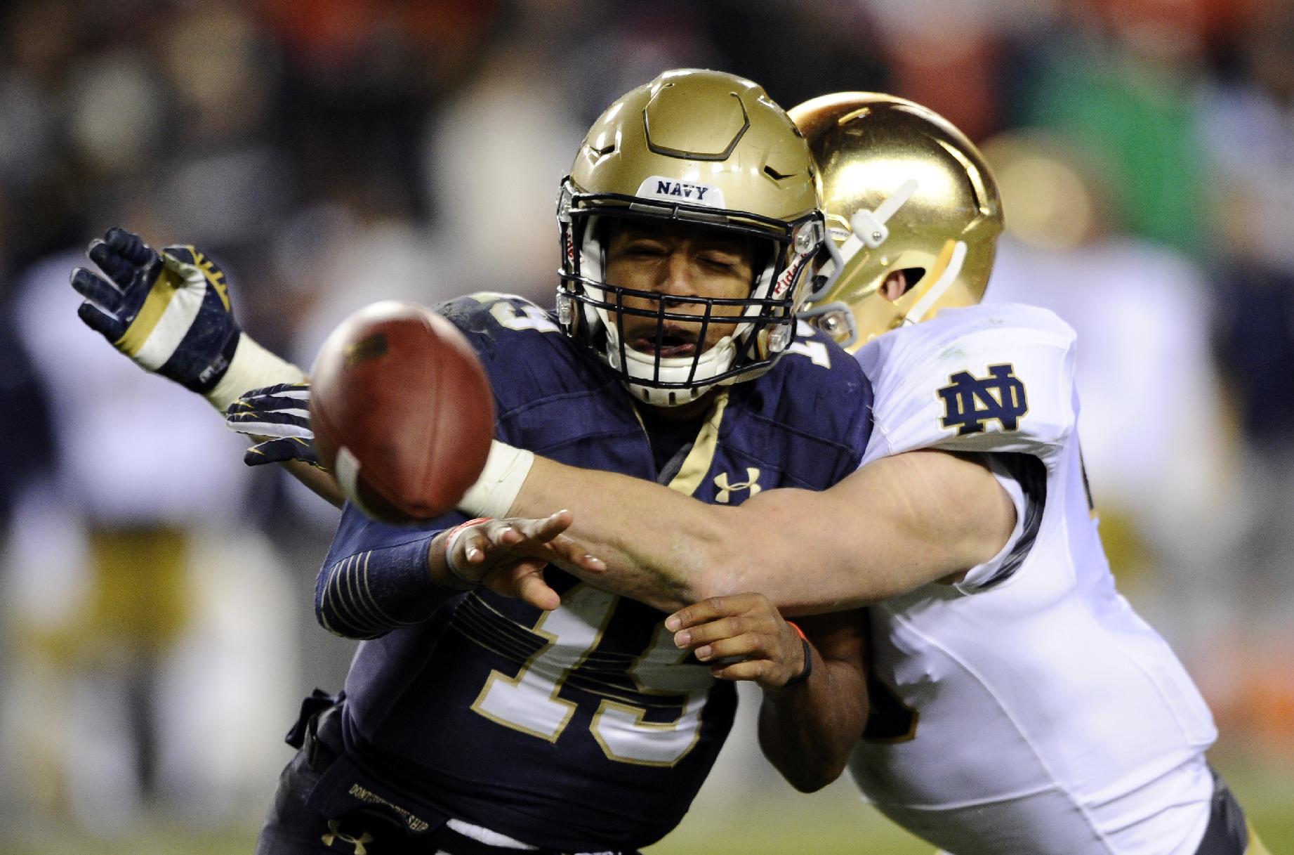 Navy quarterback Keenan Reynolds (19) pitches the ball as he is hit by a Notre Dame defender during the first half of an NCAA college football game, Saturday, Nov. 1, 2014, in Landover, Md. (AP Photo/Nick Wass)