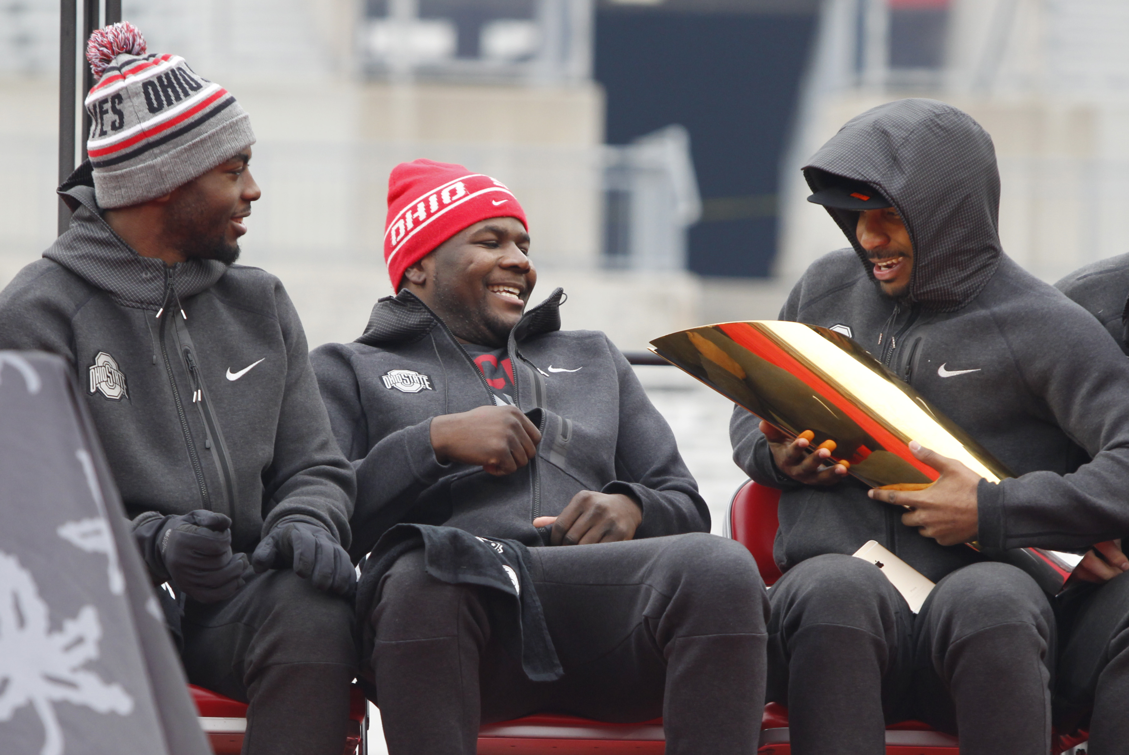 Ohio State football quarterbacks J.T. Barrett, left, Cardale Jones and Braxton Miller look at the College Football Playoff national championship trophy during a celebration of the Buckeyes national championship at Ohio Stadium in Columbus, Ohio, Saturday, Jan. 24, 2015. (AP Photo/Paul Vernon)