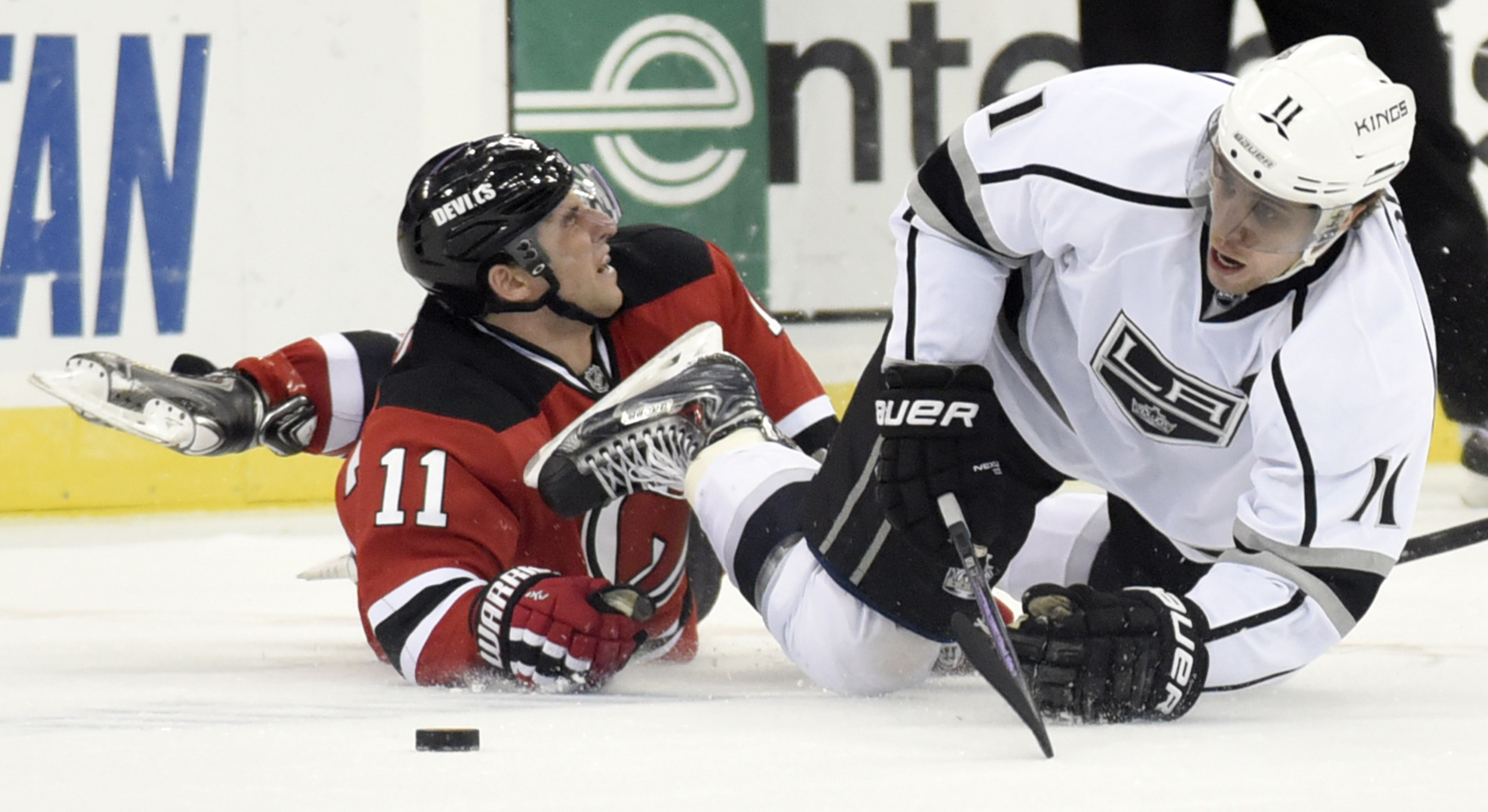 Los Angeles Kings' Anze Kopitar, right, is tripped by New Jersey Devils' Stephen Gionta during the first period of an NHL hockey game Monday, March 23, 2015, in Newark, N.J. (AP Photo/Bill Kostroun)