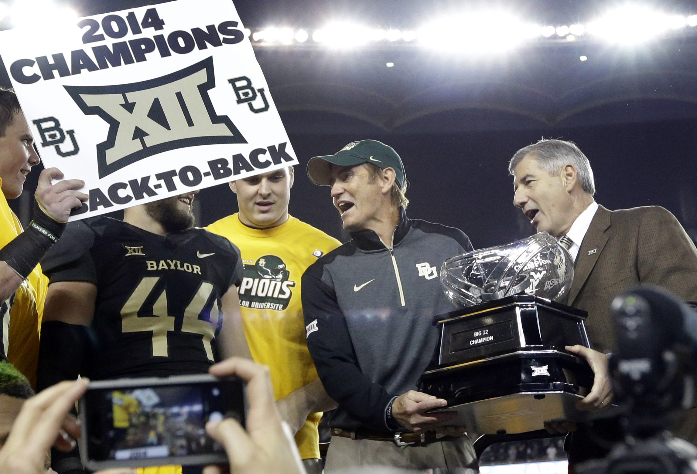 Big 12 Commissioner Bob Bowlsby, right, presents Baylor head coach Art Briles, center, with the conference trophy after their 38-27 win over Kansas State in an NCAA college football game, Saturday, Dec. 6, 2014, in Waco, Texas. (AP Photo/Tony Gutierrez)