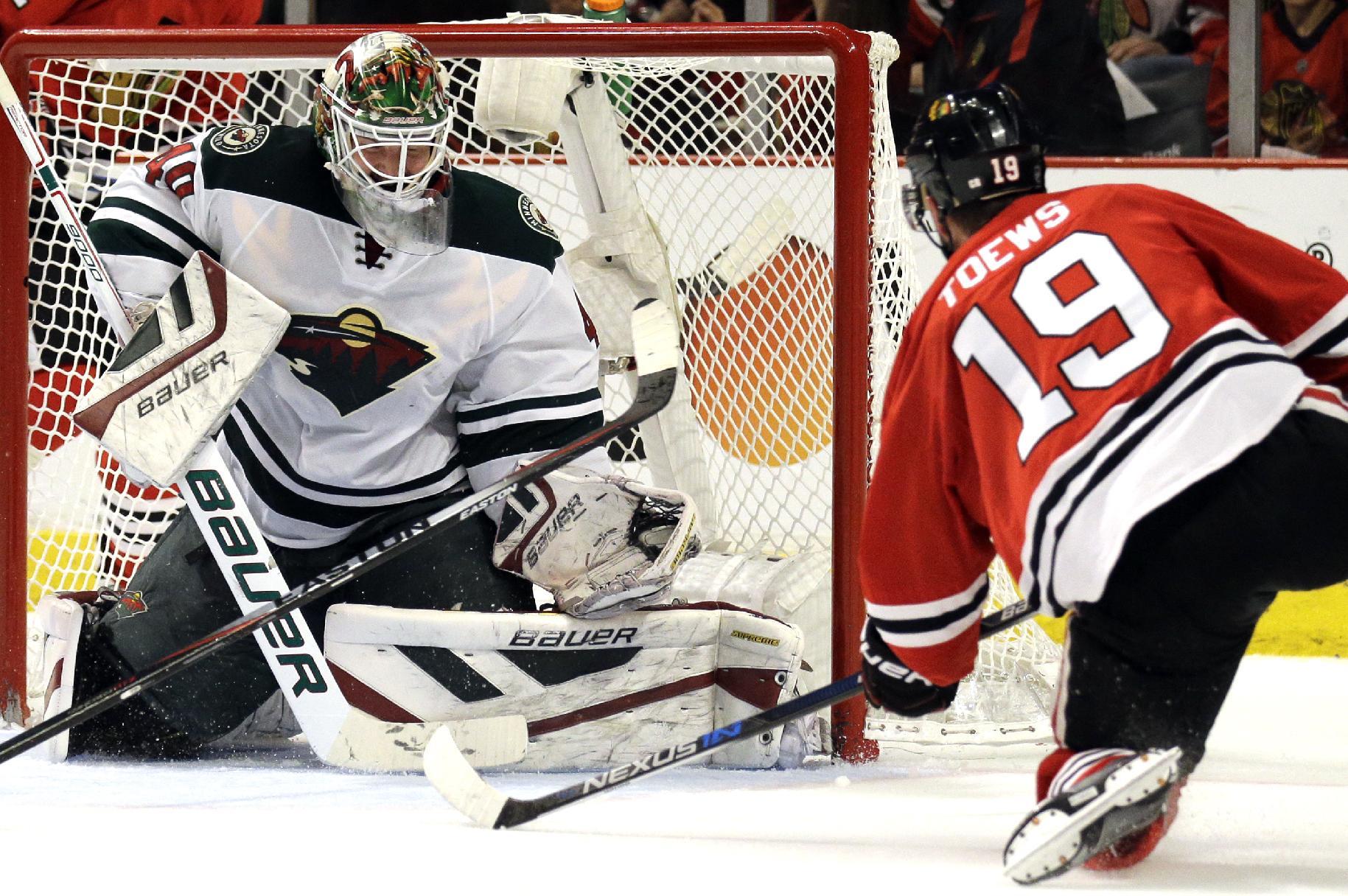 Minnesota Wild goalie Devan Dubnyk, left, fails to stop a shot and goal by Chicago Blackhawks center Jonathan Toews, right, during the second period of Game 2 in the second round of the NHL Stanley Cup hockey playoffs in Chicago, Sunday, May 3, 2015. (AP Photo/Nam Y. Huh)