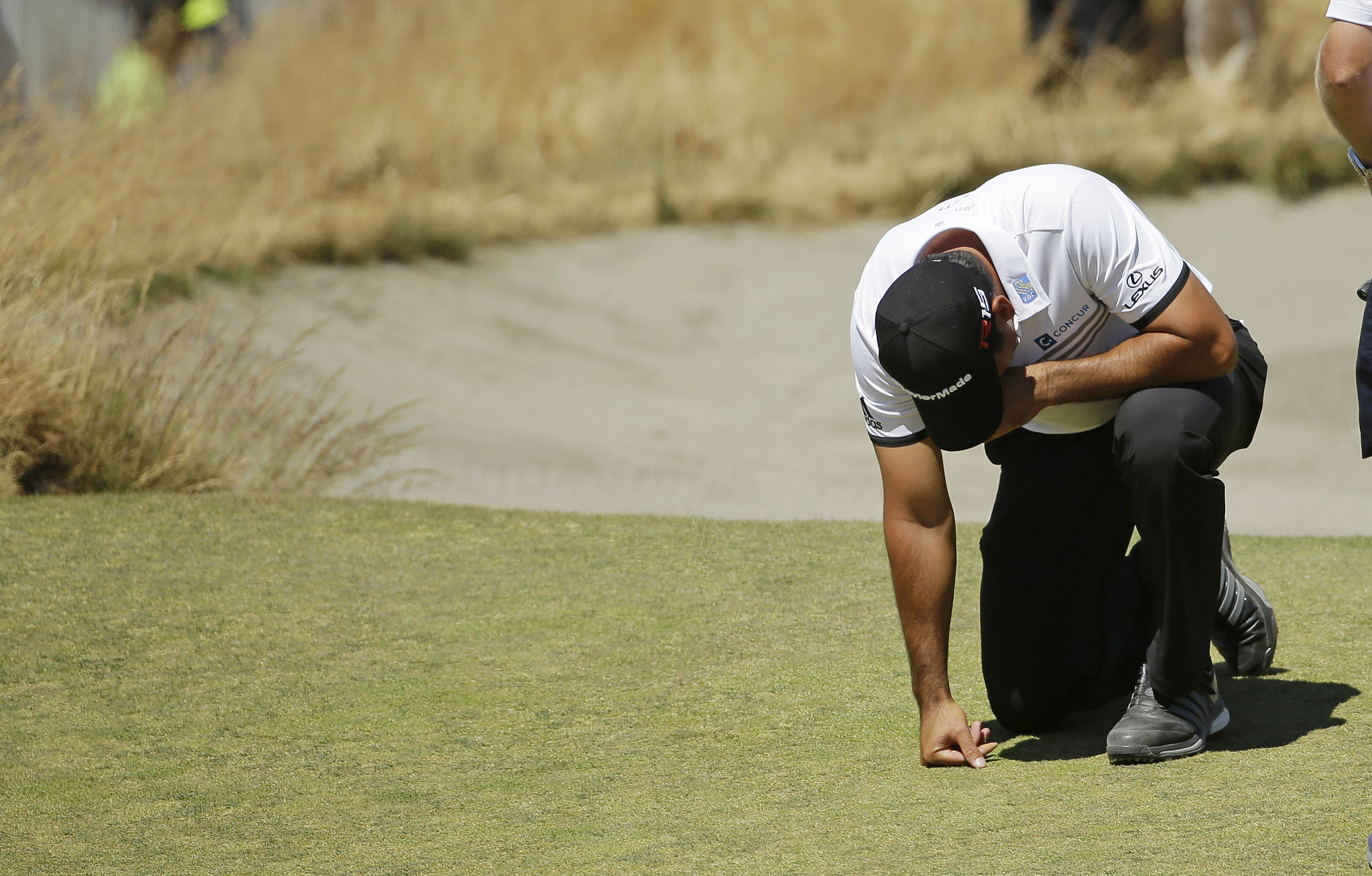 Jason Day, of Australia, kneels while waiting to putt on the ninth hole after having collapsed earlier in the fairway during the second round of the U.S. Open golf tournament at Chambers Bay on Friday, June 19, 2015 in University Place, Wash. (AP Photo/Ted S. Warren)