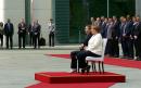 Angela Merkel sits during national anthem after bouts of shaking