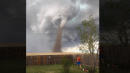 Man Nonchalantly Mows Lawn as Large Tornado Swirls Behind Him